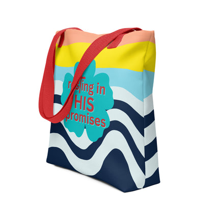 Angled view of tote bag with red straps, peach and yellow top bands, navy wave print, and “resting in HIS promises” clover design.