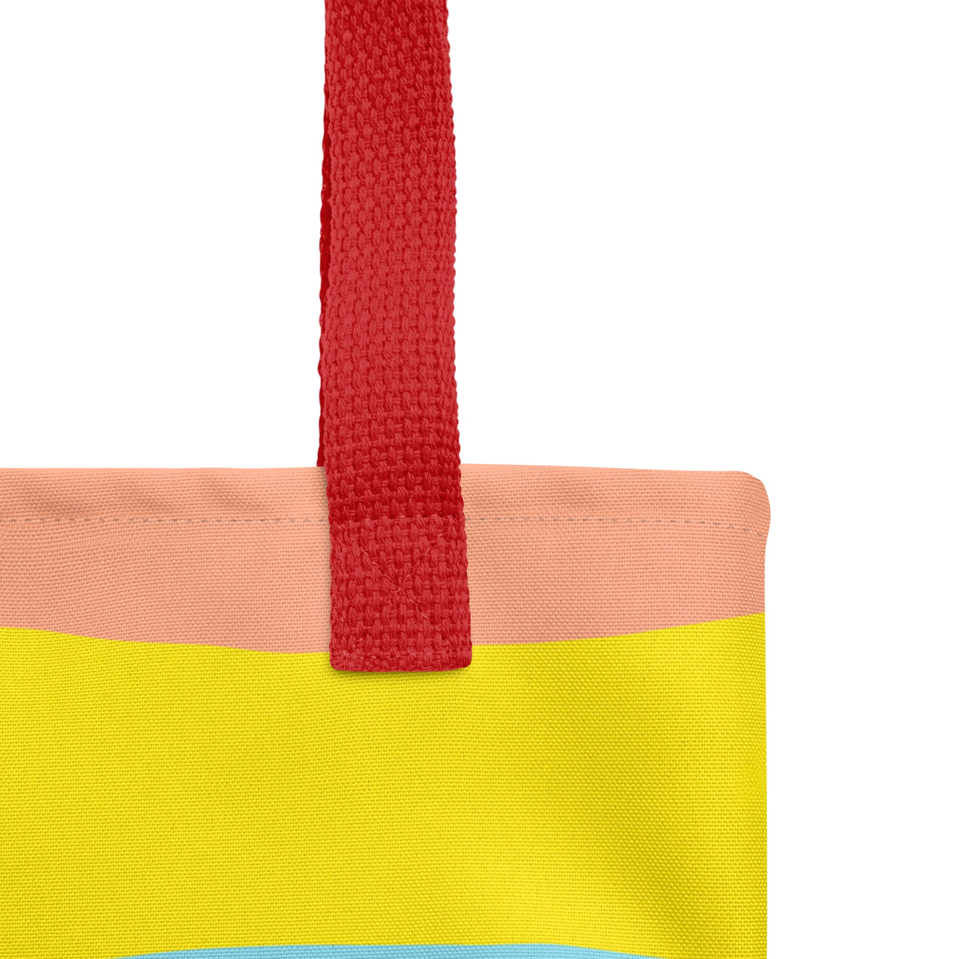 Close-up of red woven handle and stitched top edge on the tote bag’s peach and yellow color-block fabric.