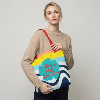 Lifestyle photo of a person carrying the tote bag with red straps, wavy stripe design, and teal “resting in HIS promises” clover graphic.