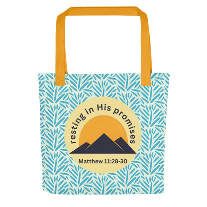 Front view of “Resting in His Promises” Christian tote bag with yellow handles, blue leaf pattern, and Matthew 11:28–30 mountain emblem.