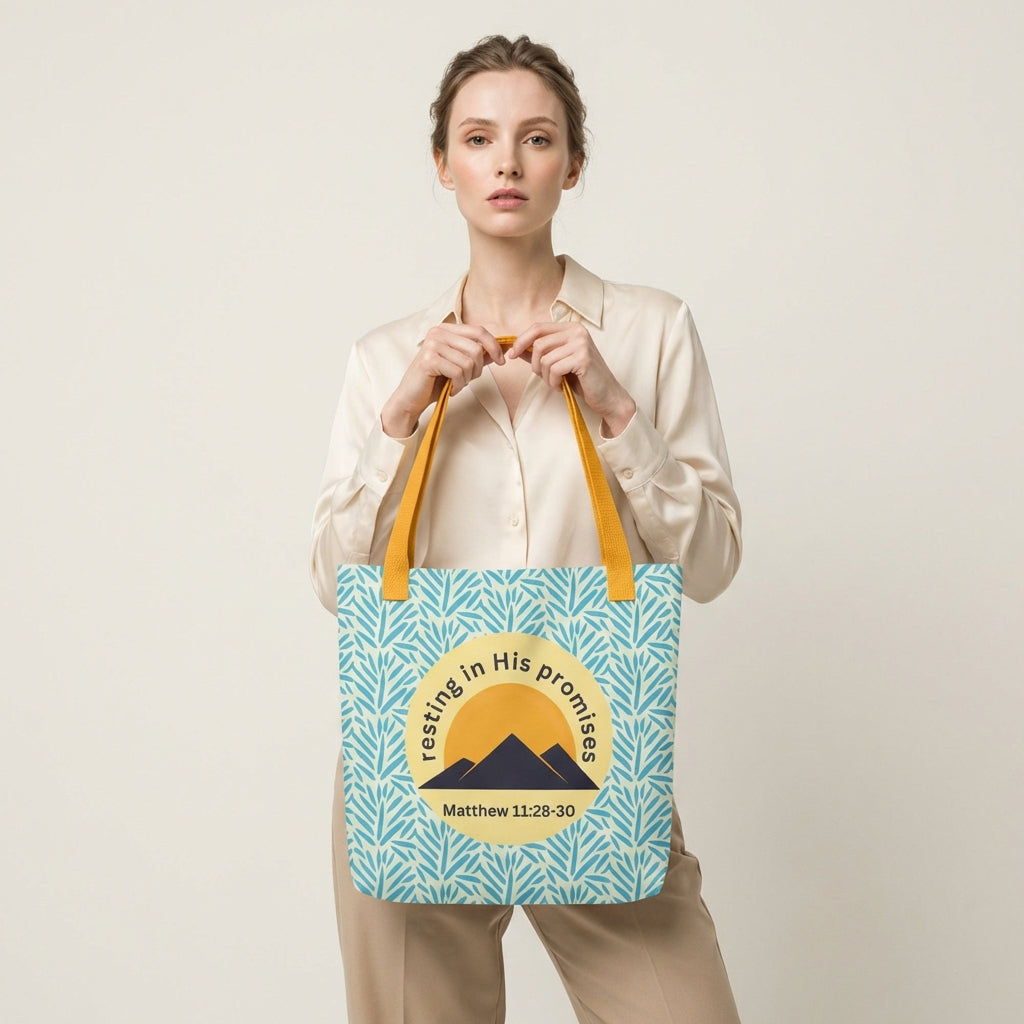 Lifestyle shot of a person carrying the “Resting in His Promises” Matthew 11:28–30 Christian tote with yellow handles and blue botanical pattern.