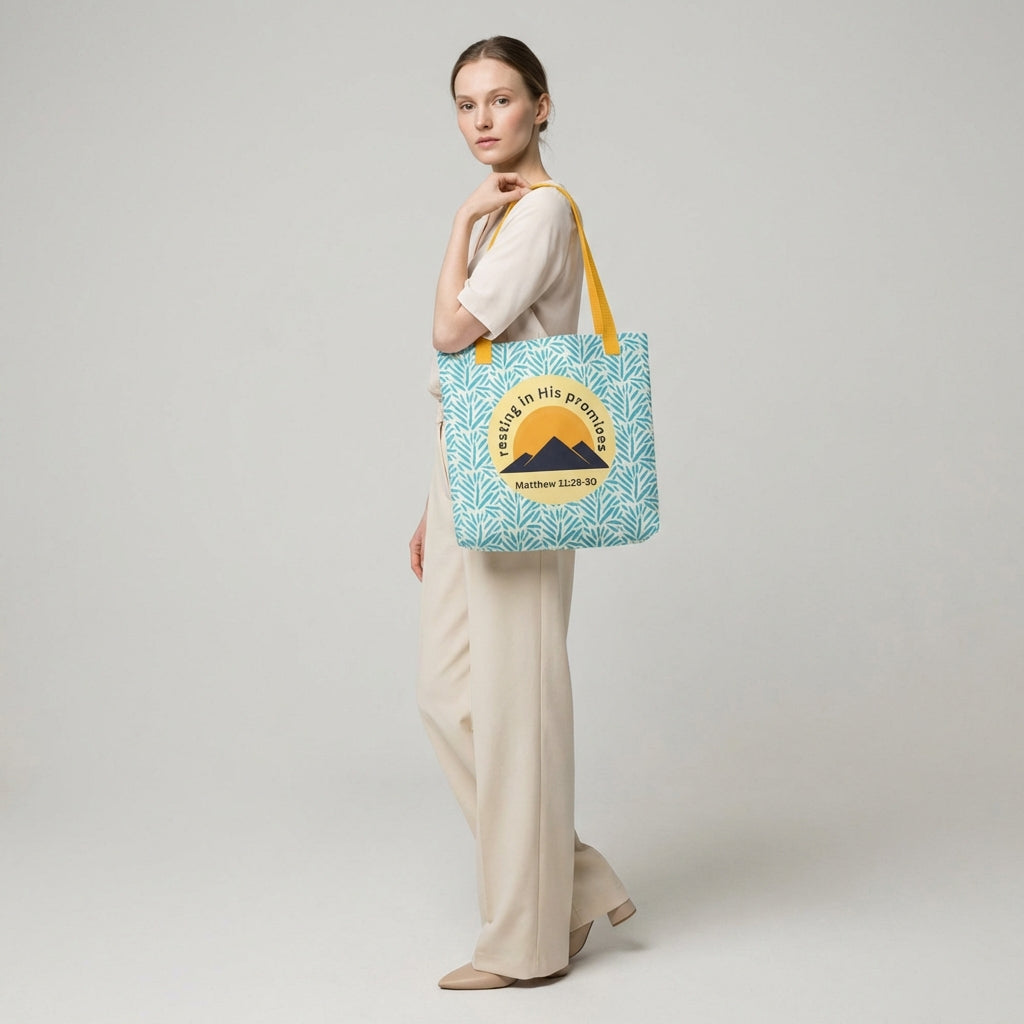 Lifestyle shot of a person carrying the “Resting in His Promises” Matthew 11:28–30 Christian tote with yellow handles and blue botanical pattern.