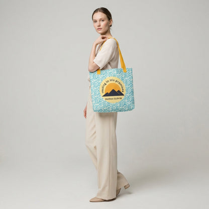 Lifestyle shot of a person carrying the “Resting in His Promises” Matthew 11:28–30 Christian tote with yellow handles and blue botanical pattern.