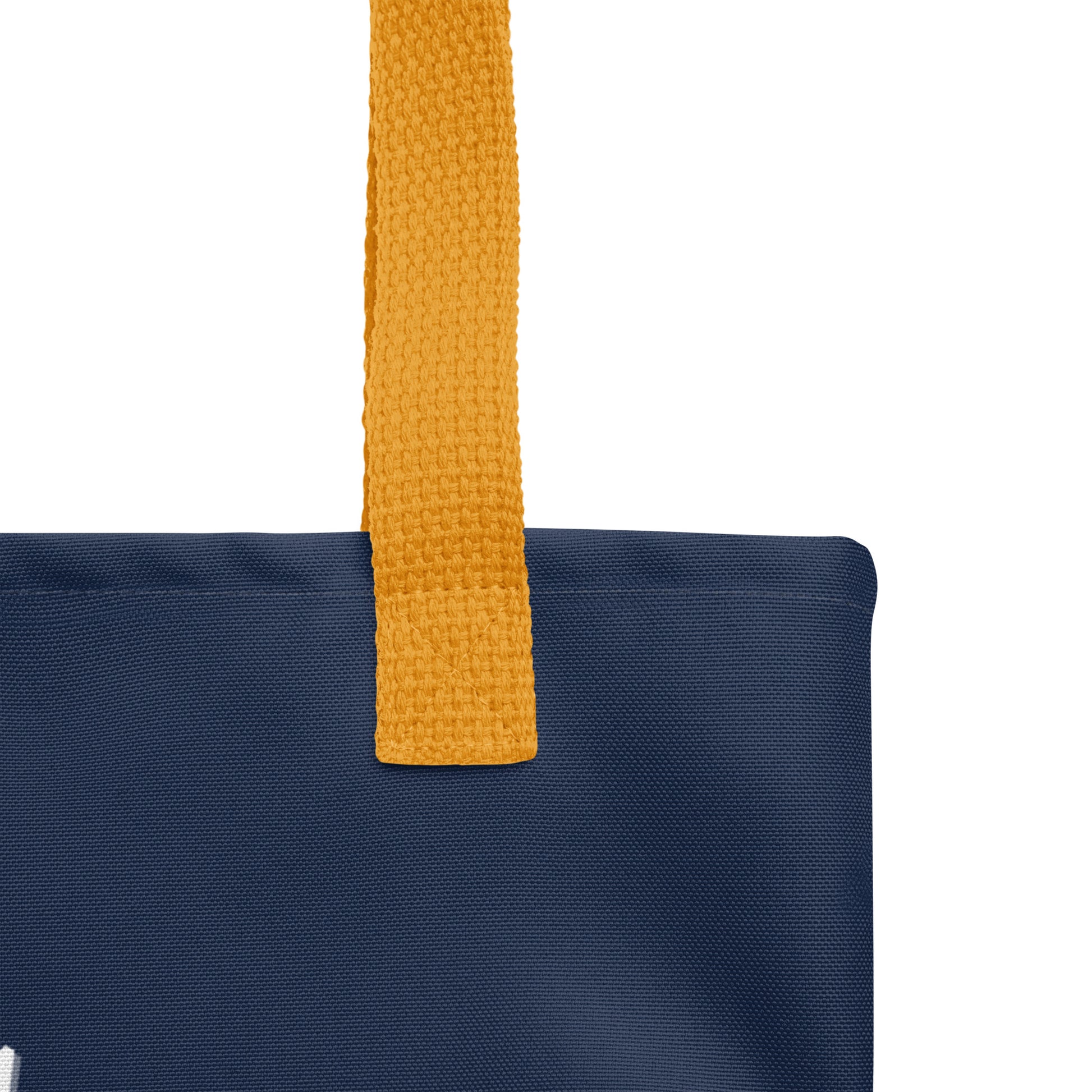 Close-up of the mustard yellow handle attachment on the navy tote, showing the canvas texture and reinforced stitching.