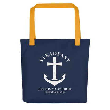 Front view of a navy blue Christian tote bag with mustard yellow straps, featuring a white anchor-and-cross graphic and the text “STEADFAST” and “JESUS IS MY ANCHOR” with “HEBREWS 6:19” below.