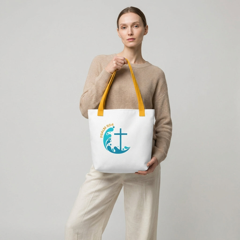 Model holding a white tote bag with yellow handles featuring the “Psalm 93:4” wave-and-cross graphic.