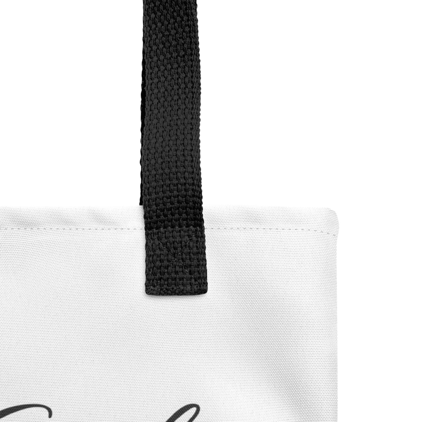 Close-up of the white tote fabric and black strap, highlighting the stitching, textured canvas, and strap weave detail.