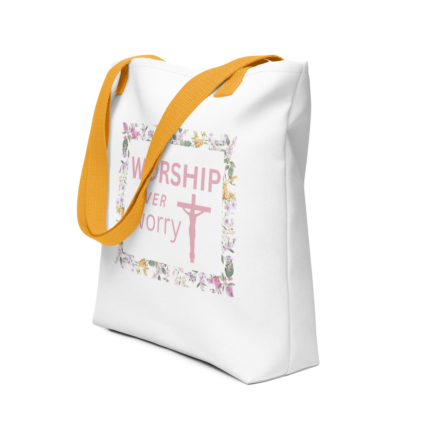 Angled view of the white tote with mustard-yellow handles, showing the “WORSHIP over worry” design framed by pastel flowers and leaves.