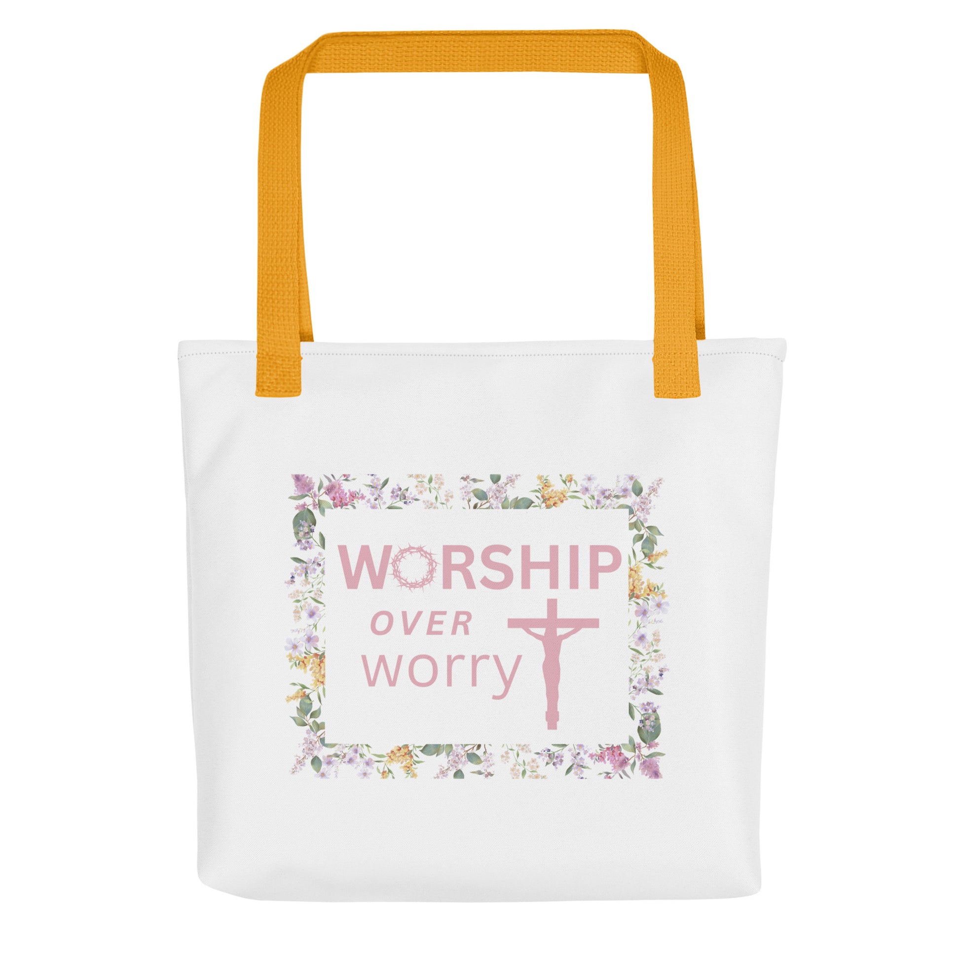 White tote bag with mustard-yellow straps featuring “WORSHIP over worry” and a pink cross inside a floral border.
