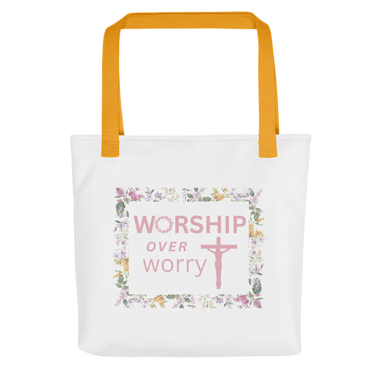 White tote bag with mustard-yellow straps featuring “WORSHIP over worry” and a pink cross inside a floral border.