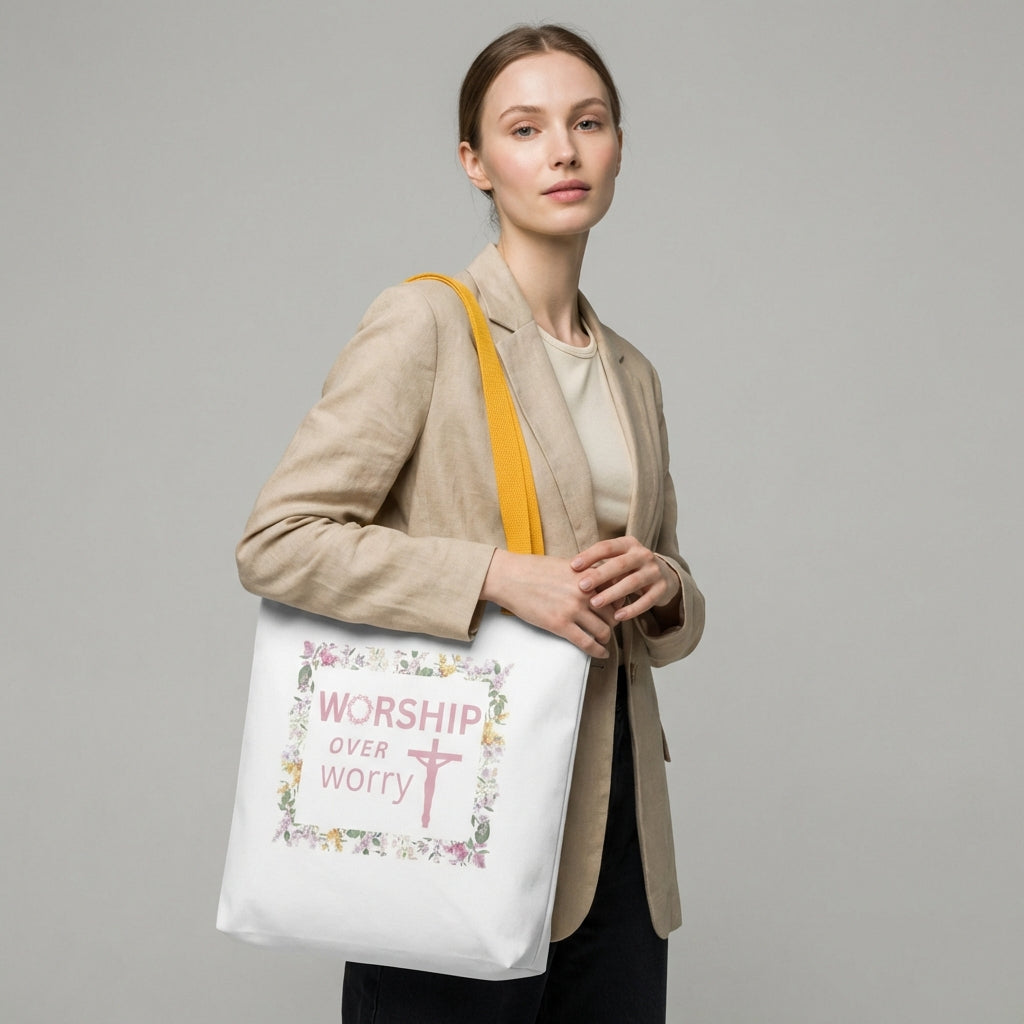 Lifestyle shot of a model wearing a white tote with mustard-yellow straps and a floral framed “WORSHIP over worry” cross design.